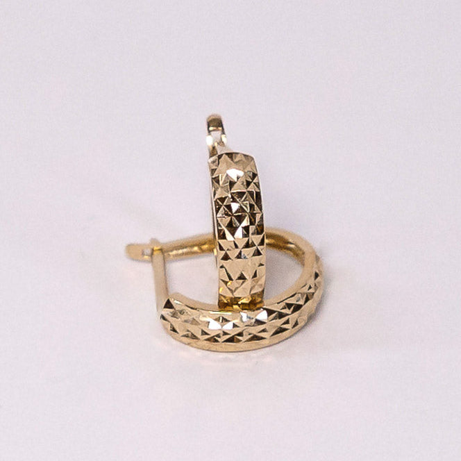 Gold hoop earring on a light gray background