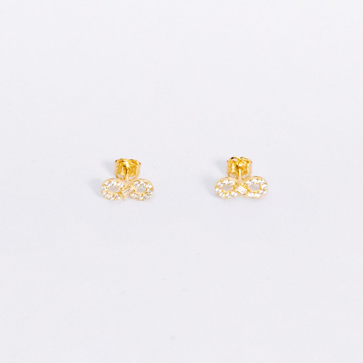 Gold stud earrings on a light gray background
