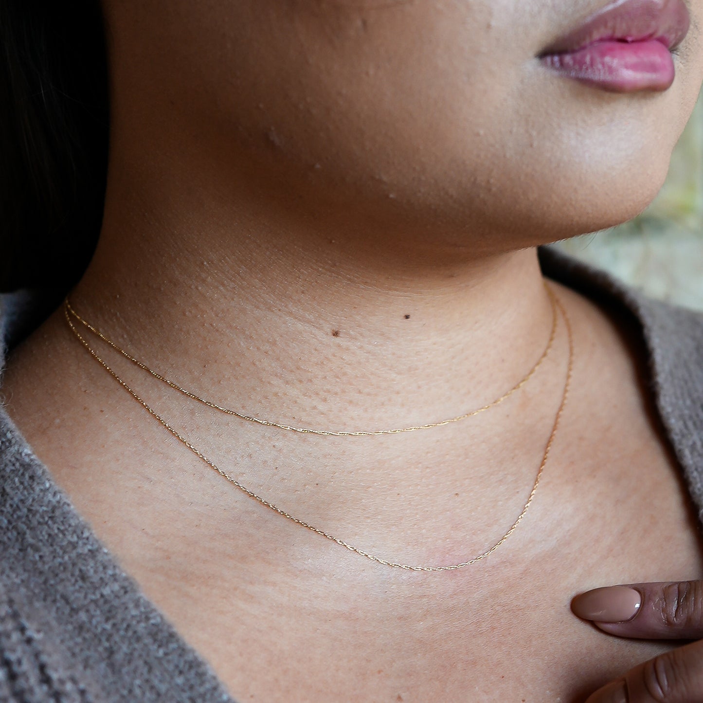Close-up of a person wearing a delicate gold necklace.