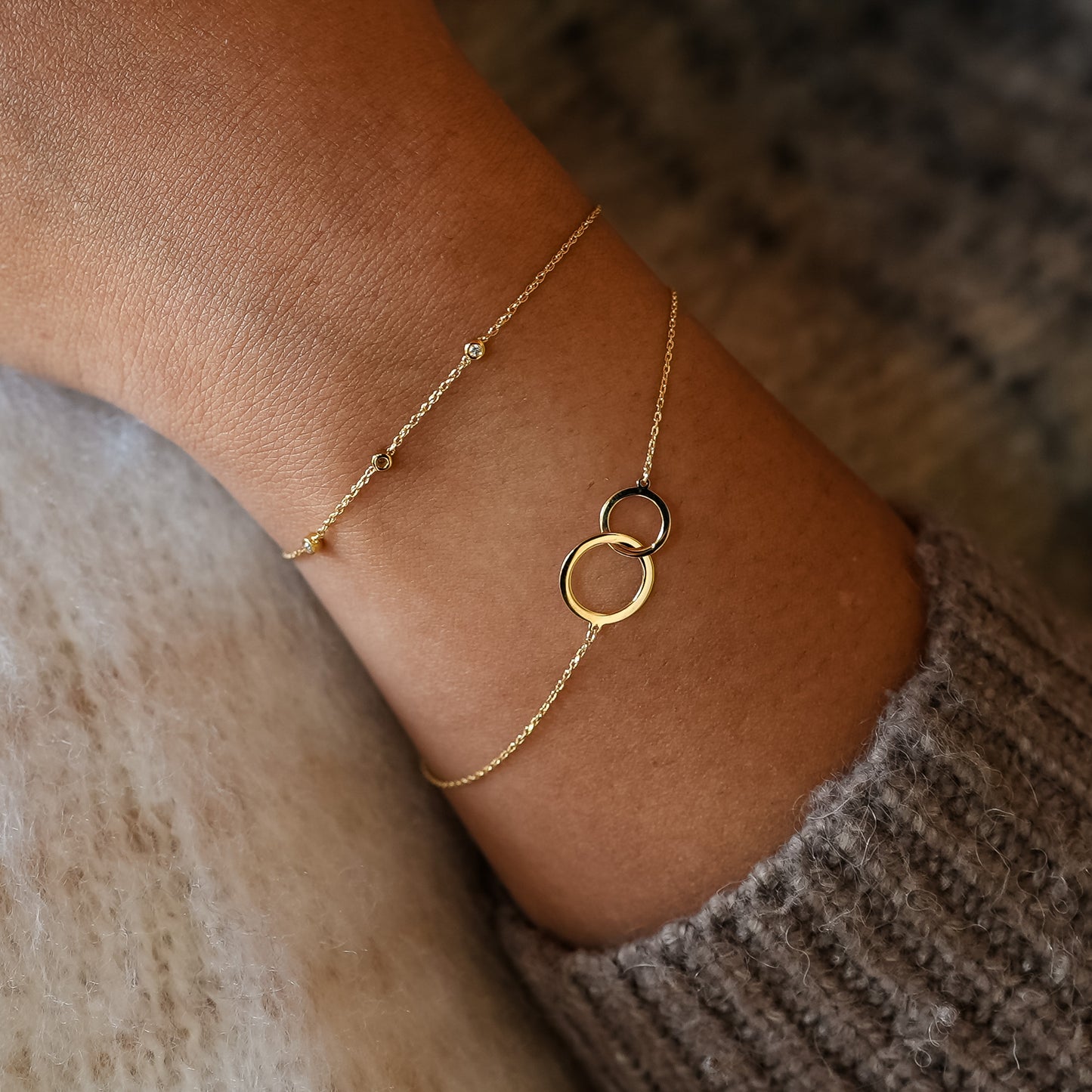 Gold anklet with interlocking rings on a person's ankle against a neutral background