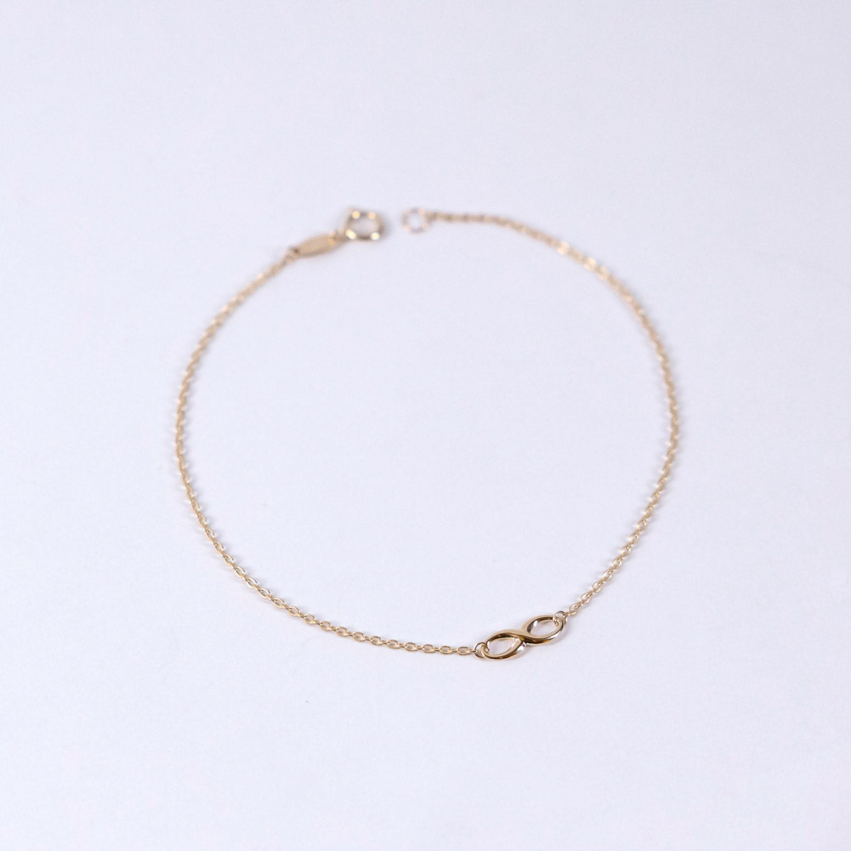 Gold bracelet with a small clasp on a light gray background