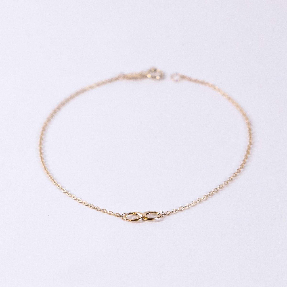 Gold bracelet with a unique clasp design on a light gray background