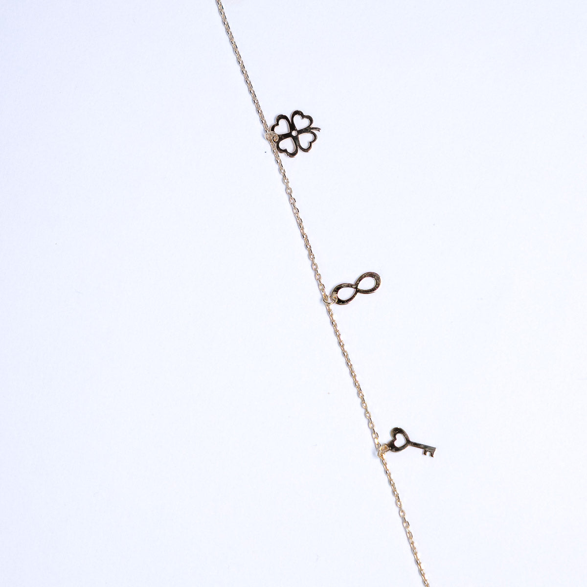 Necklace with floral, infinity, and key pendants on a light background