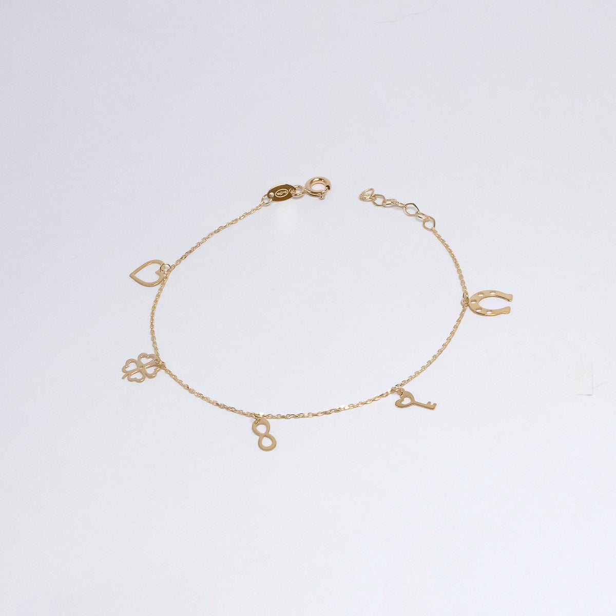 Gold bracelet with various charms on a light gray background