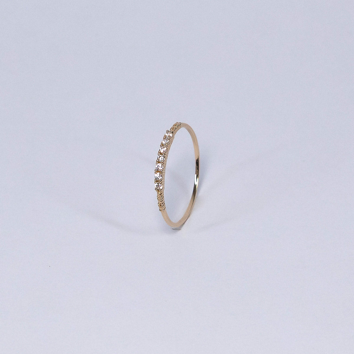 Gold ring with small stones on a light gray background