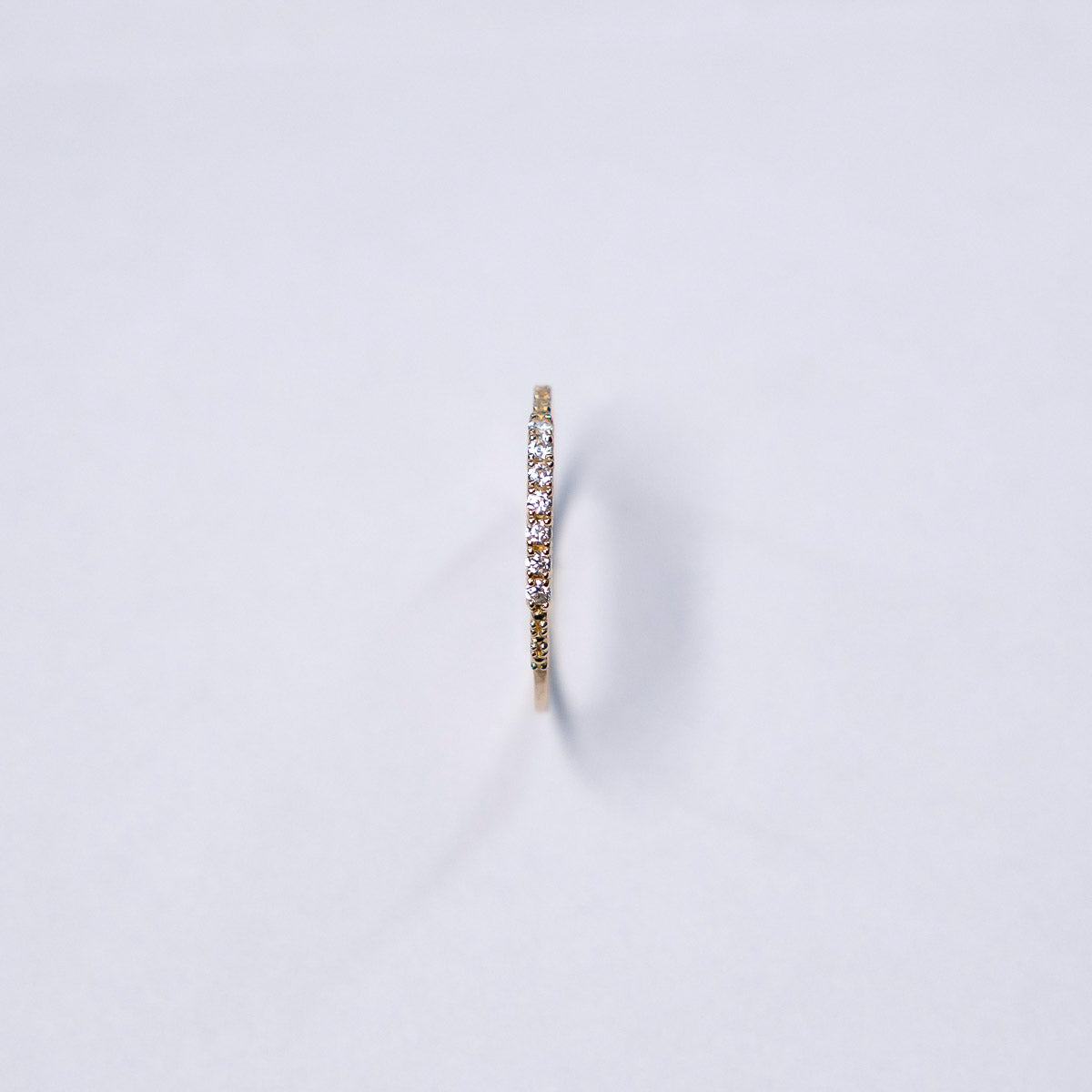 Gold earring with small diamonds on a light gray background
