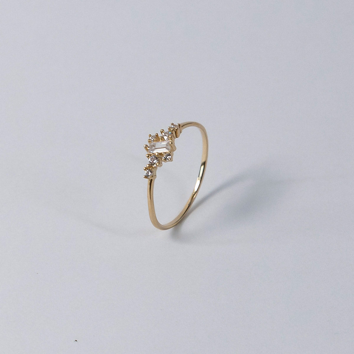 Gold ring with small diamonds on a light gray background