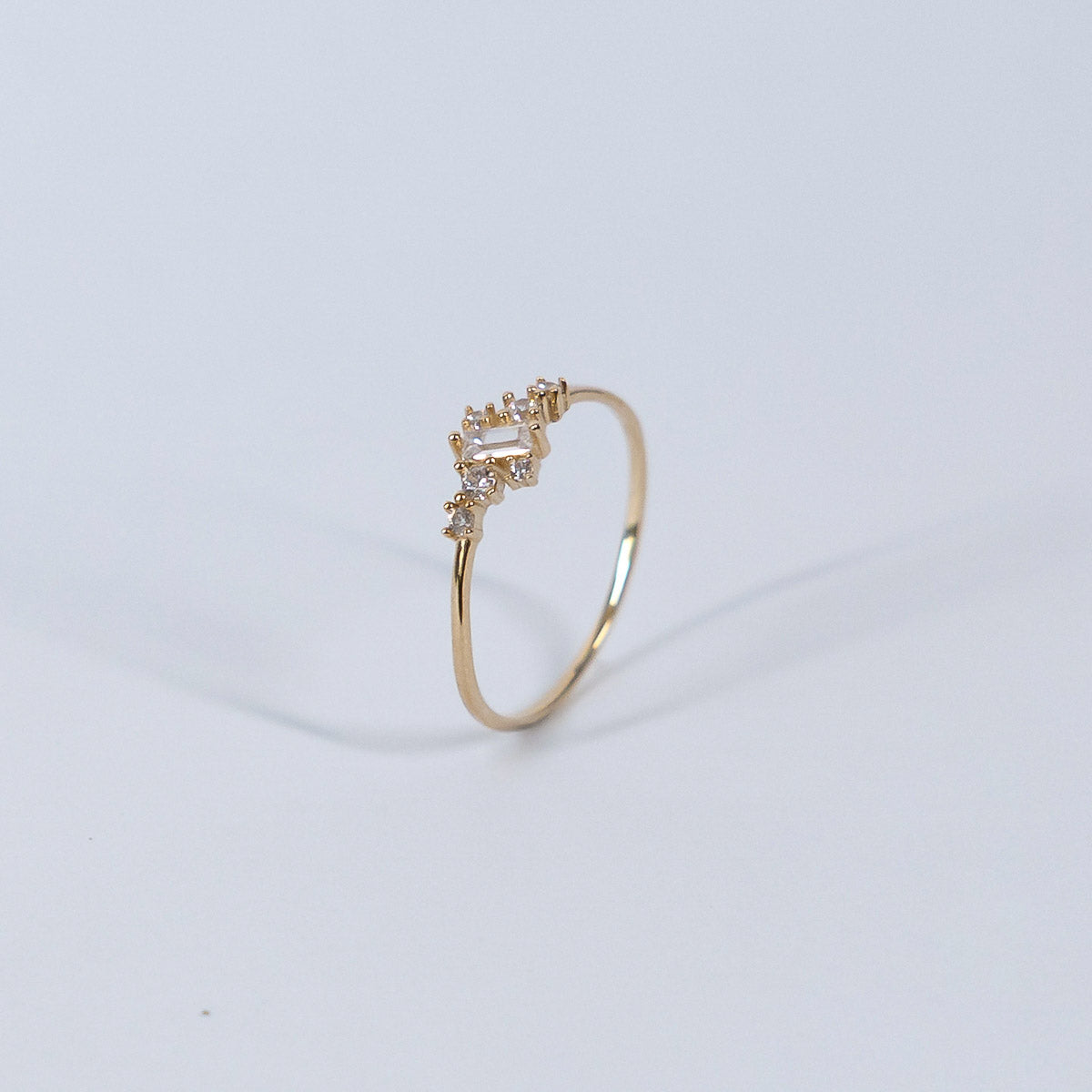 Gold ring with small diamonds on a light gray background