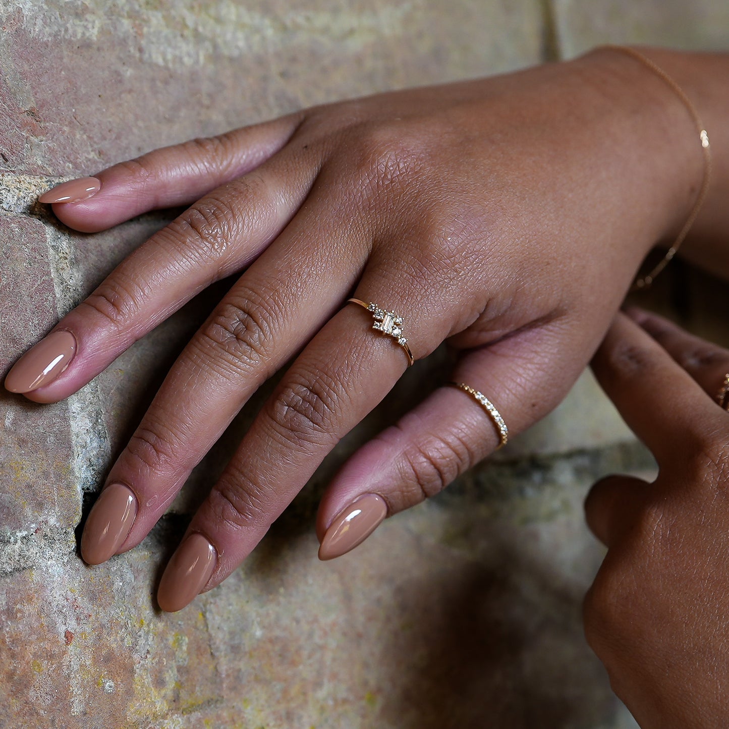 Close-up of a hand with two gold rings on a textured surface