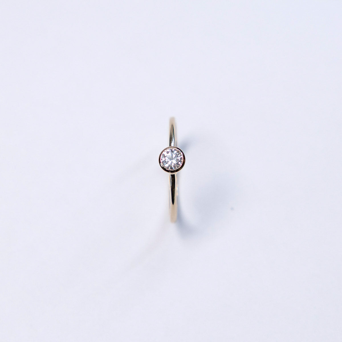 Gold ring with a diamond on a light gray background
