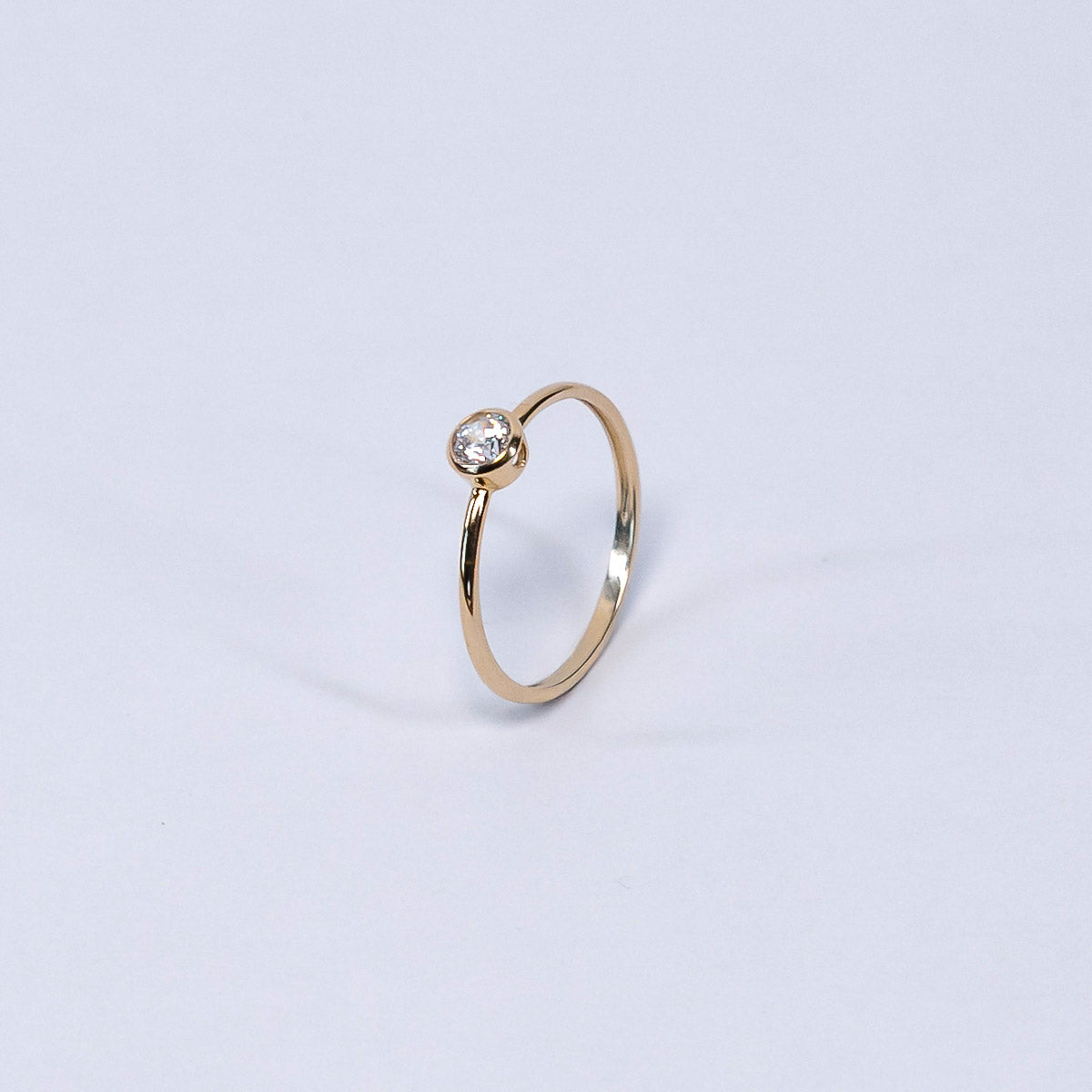 Gold ring with a diamond on a light gray background