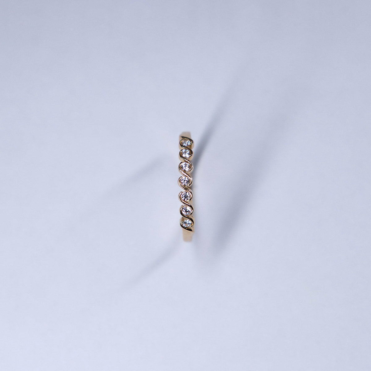 Gold ring with small diamonds on a light gray background