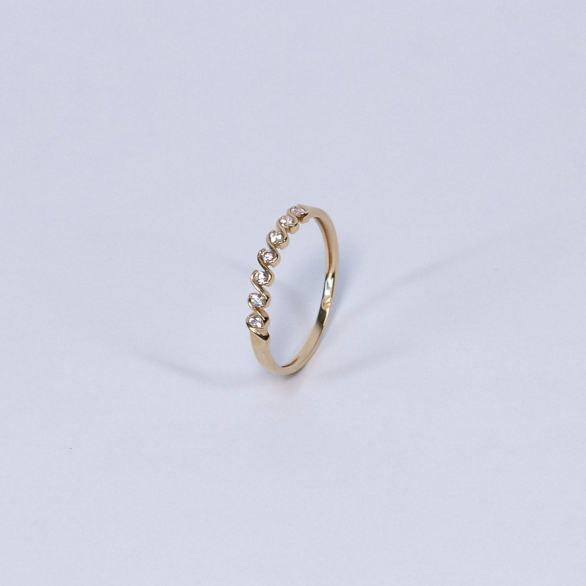 Gold ring with small stones on a light gray background