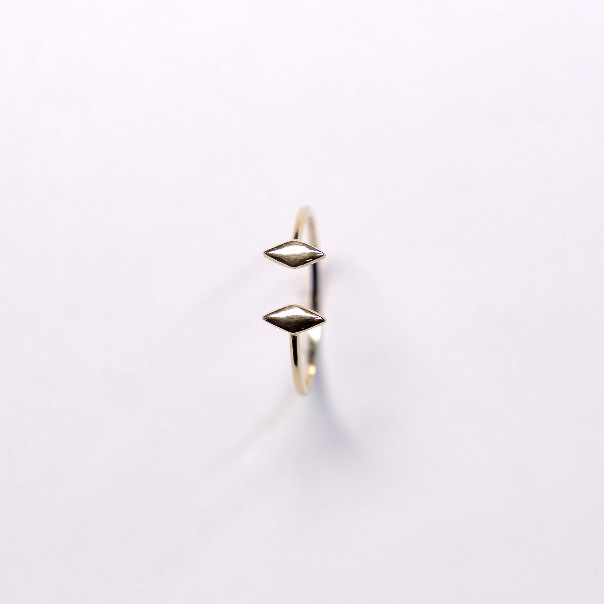 Gold ring with geometric design on a light gray background