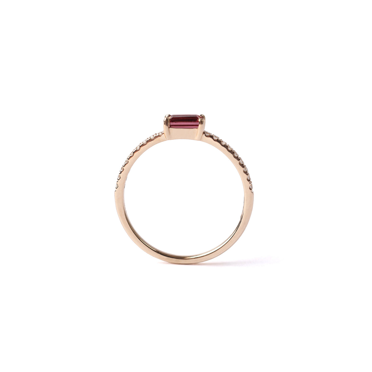 Women's solid yellow gold ring set with a central baguette cut pink tourmaline gemstone, with small round diamonds set into the shoulders on the ring on either side of the tourmaline, displayed standing up on the white background.