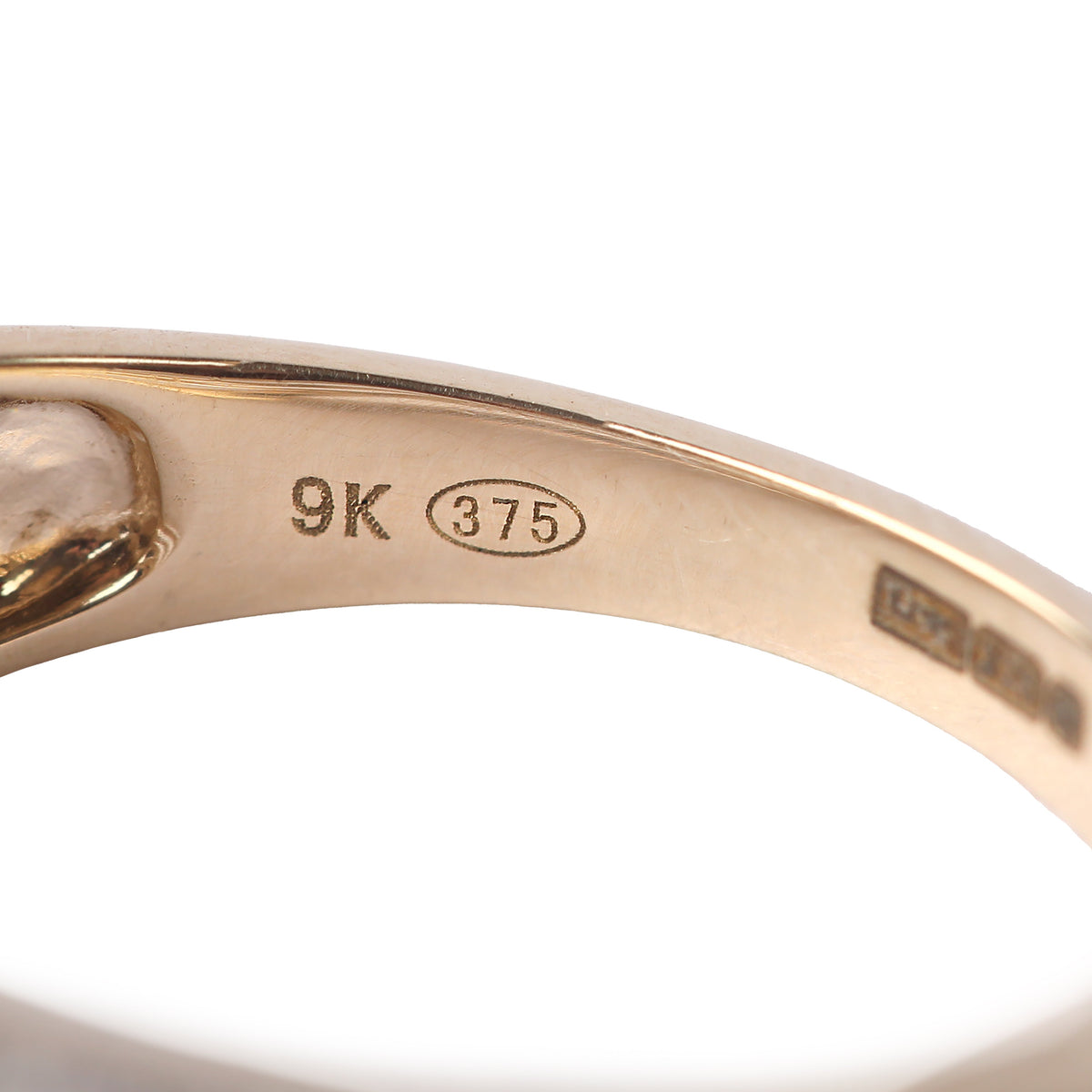 Close-up of the inside of a yellow gold ring band showing 9K (375) gold purity stamps on a white background.