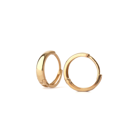 A pair of solid yellow gold huggie hoop earrings on a white background. One is facing forward the other at an angle.