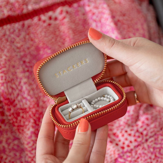 Red jewelry case with gold zipper held by a person, displaying Stackers brand.