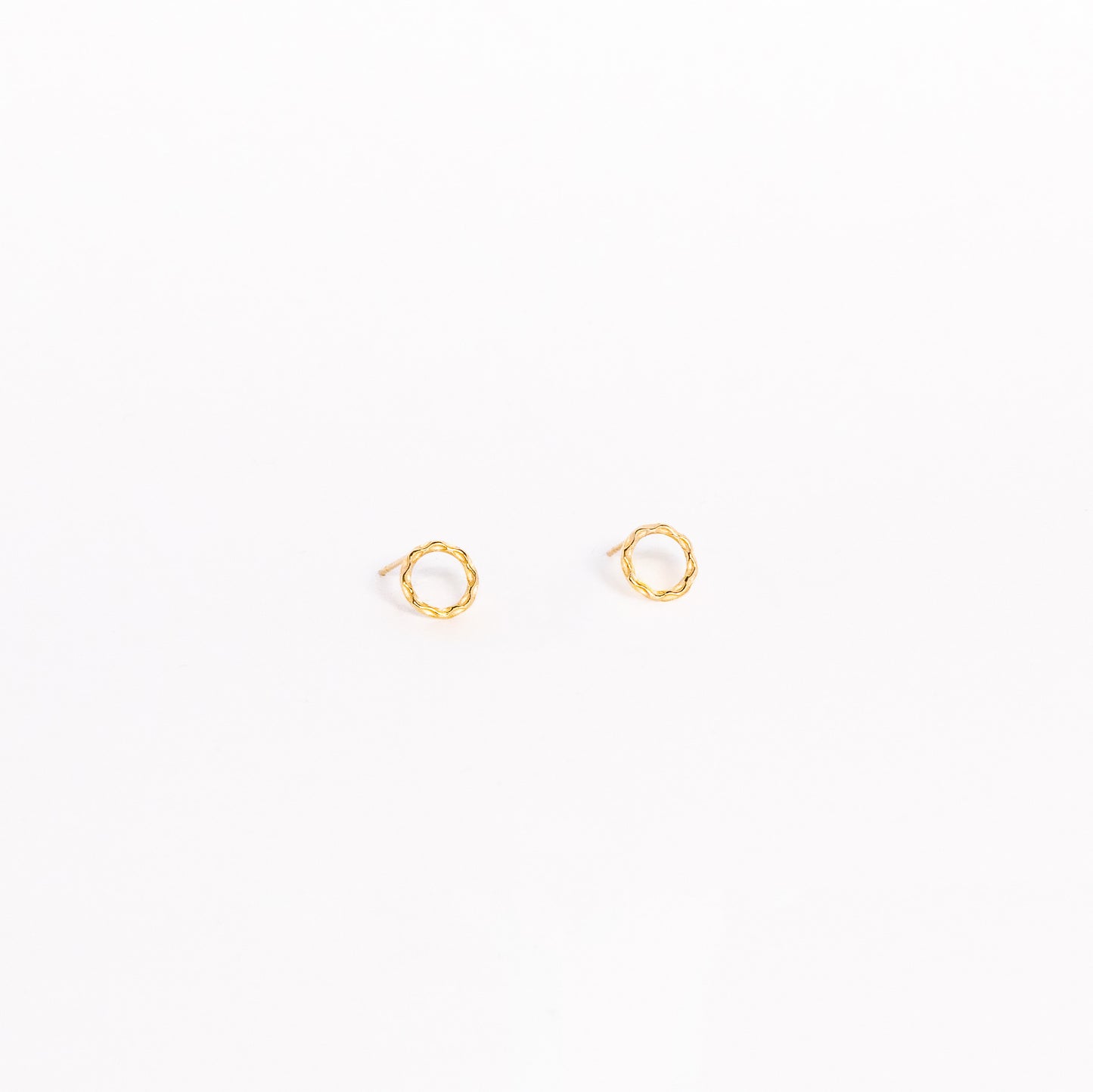 A pair of solid yellow gold circle stud earrings. Both earrings are facing forward and are set on a white background for the shopper to view.