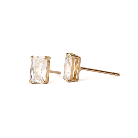 A pair of solid yellow gold and emerald cut cubic zirconia stud earrings. One earring faces forward and the other is positioned sideways showing the claw setting. Both are displayed on a white background.