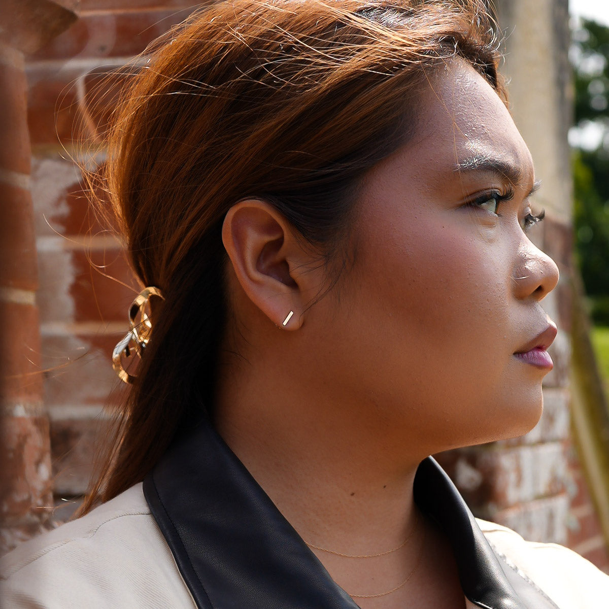 Close-up of a woman's profile with a brick wall background