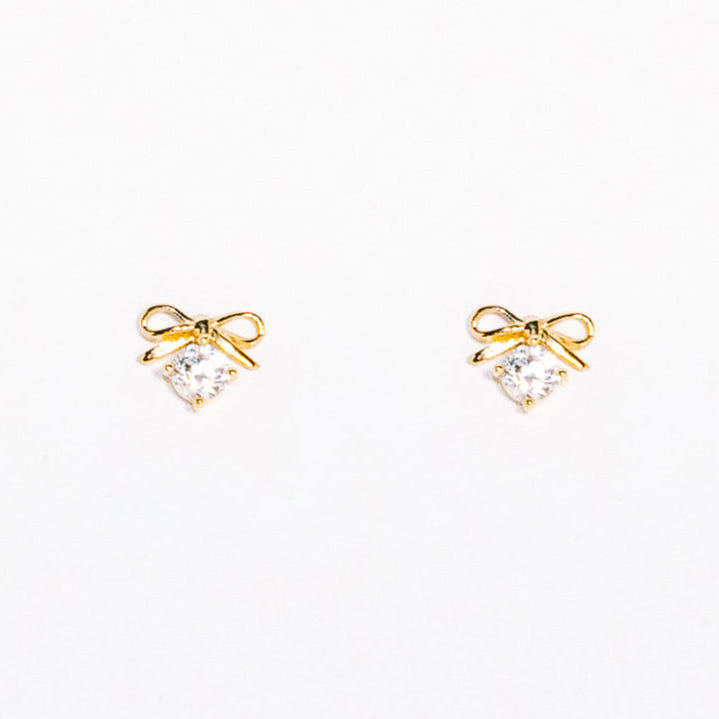 Gold bow-shaped earrings with clear gemstones on a white background