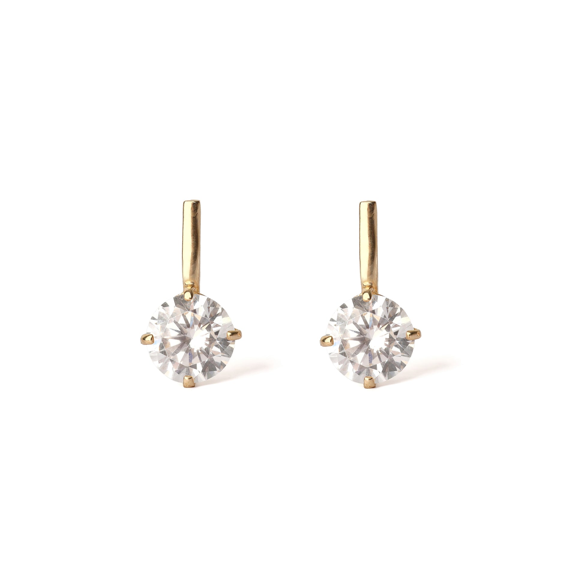 Pair of gold earrings with clear gemstones on a white background