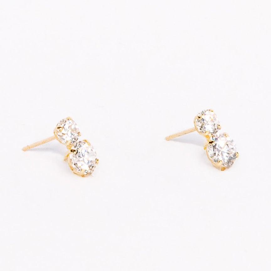 Pair of gold earrings with clear gemstones on a white background