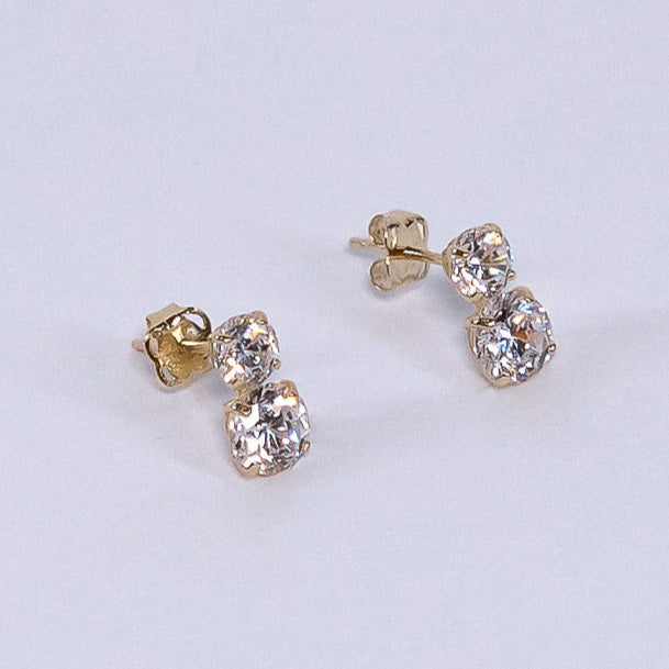 Pair of gold and diamond earrings on a light gray background