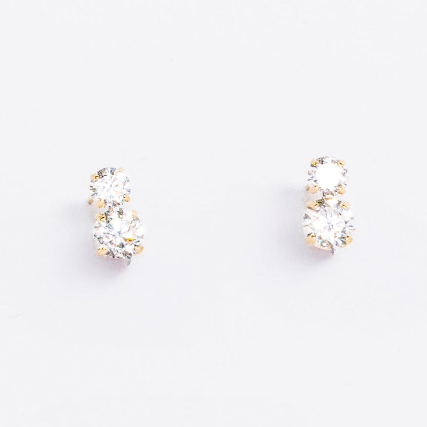 Pair of gold hoop earrings with clear gemstones on a light gray background