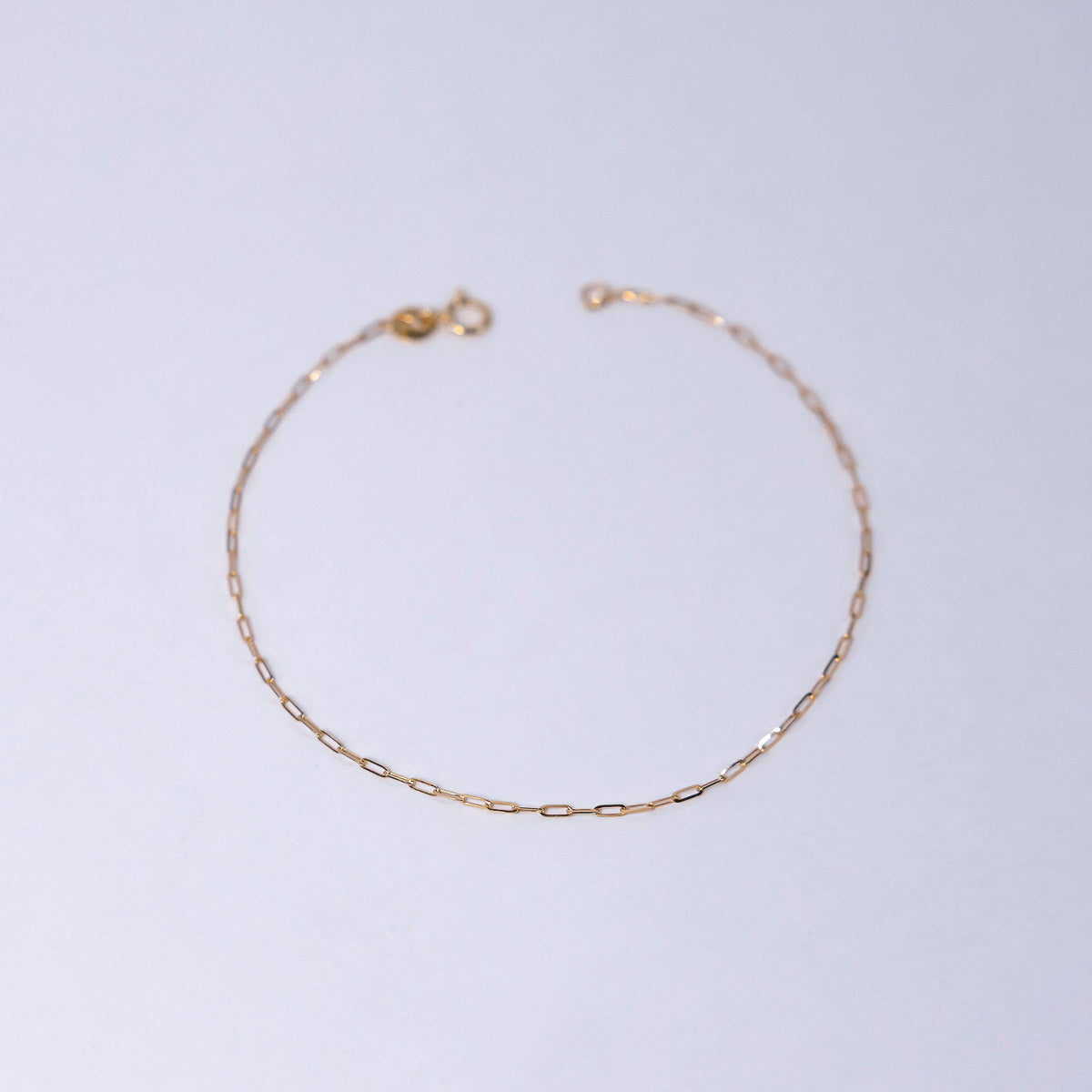 Gold chain bracelet on a light gray background