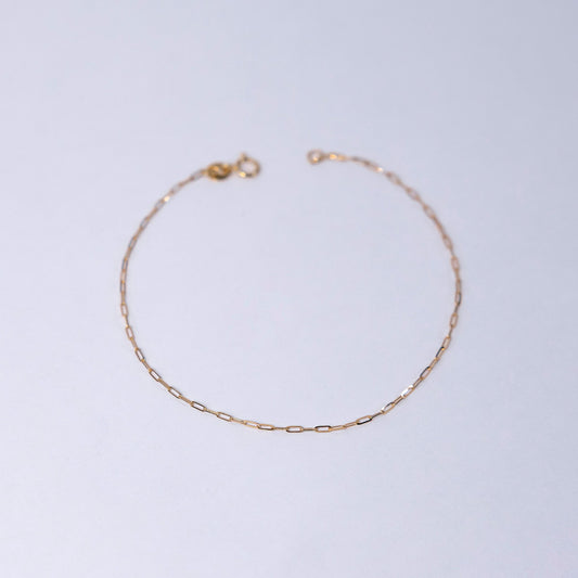 Gold chain bracelet on a light gray background