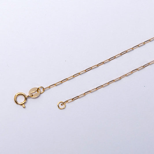 Gold chain necklace on a light gray background