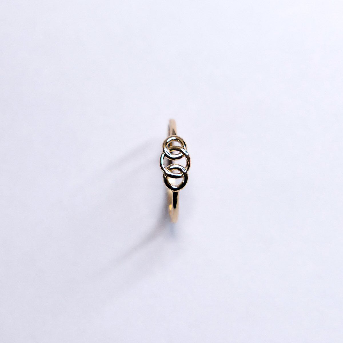 Gold ring with interlocking rings on a white background