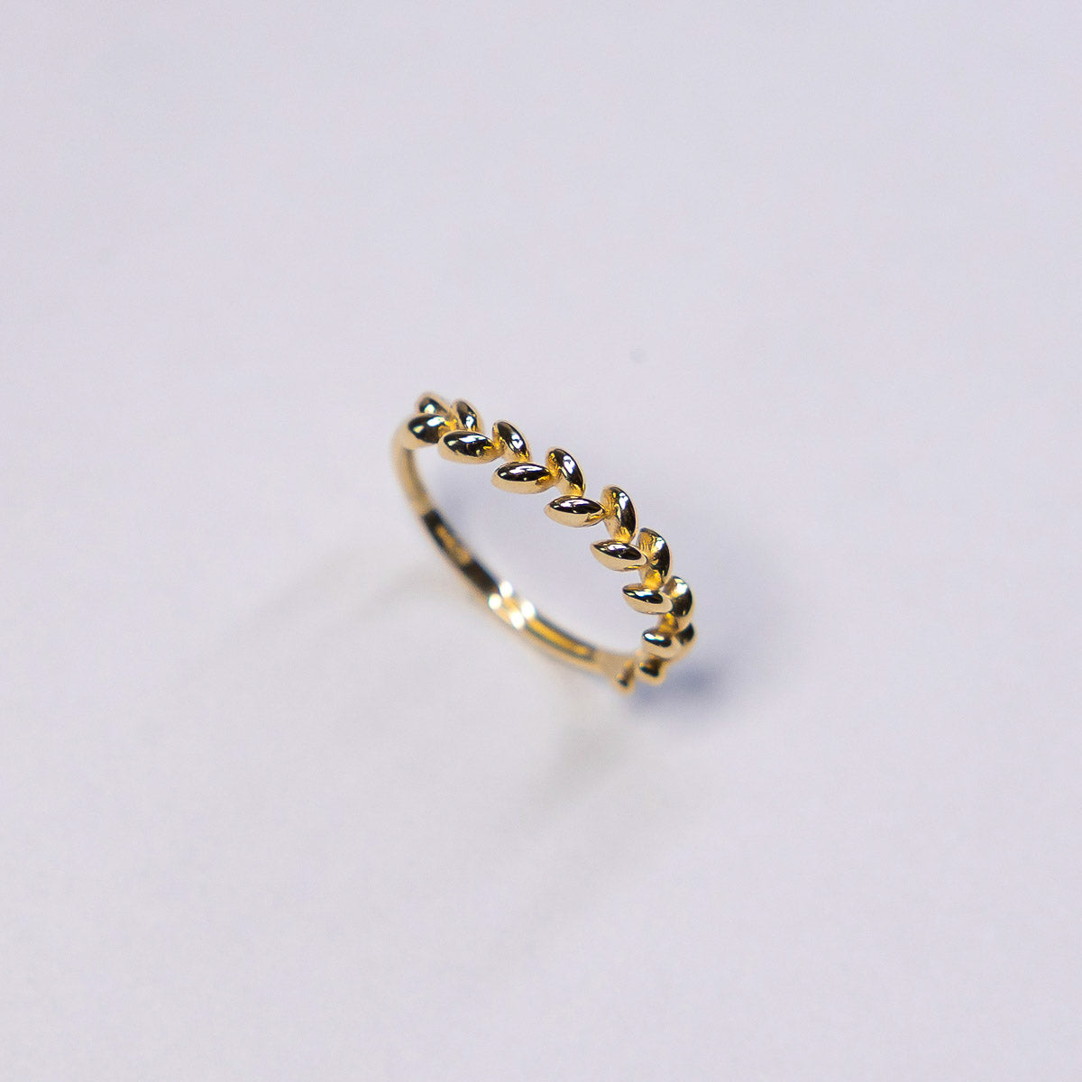 Gold ring with leaf design on a light gray background