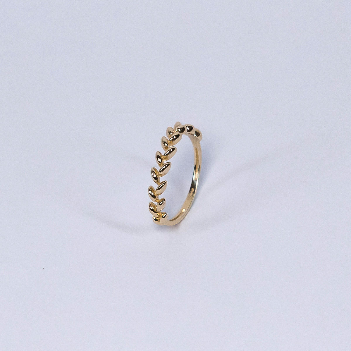 Gold ring with leaf-like design on a light gray background