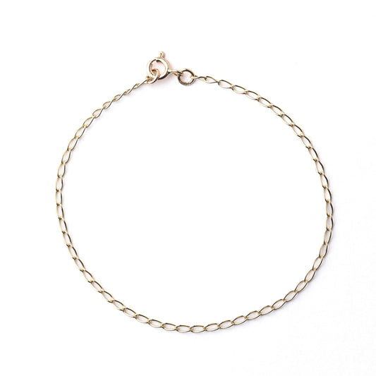 Women's solid gold curb chain bracelet on a white background