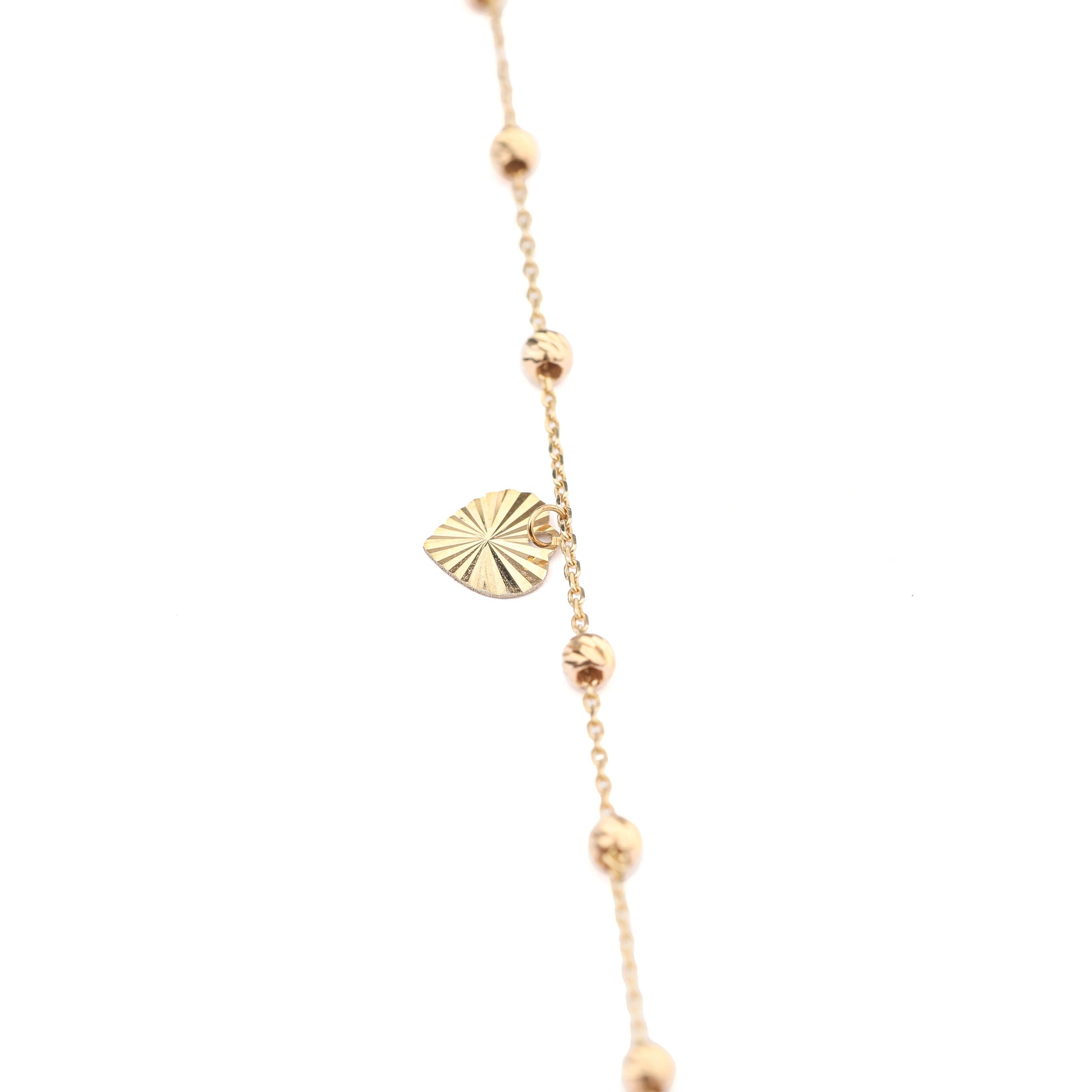 Women's 9K solid yellow gold chased heart charm bracelet with sphere embellishments on the chain on a white background