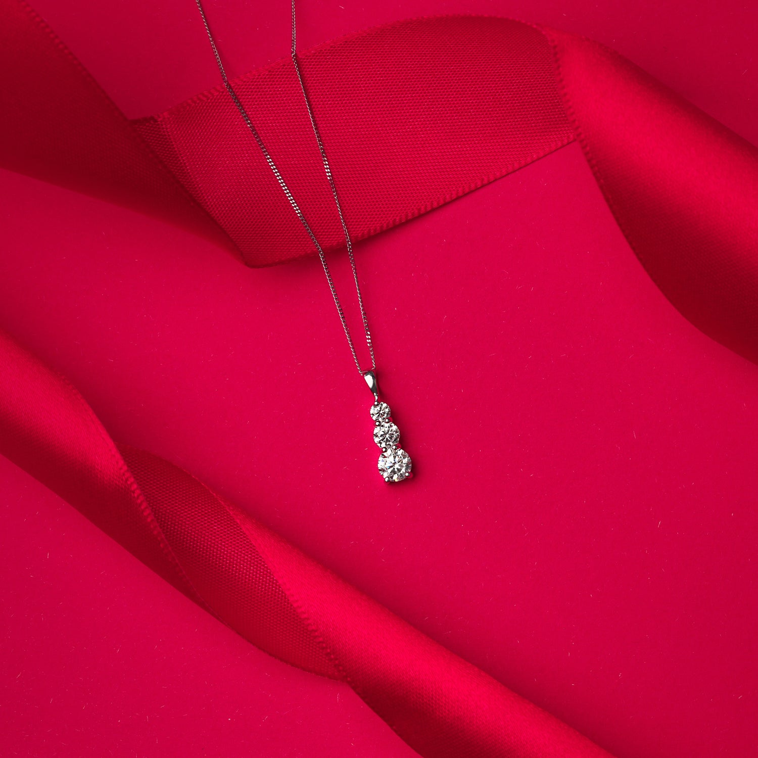 Gold necklace with a pendant on a red fabric background