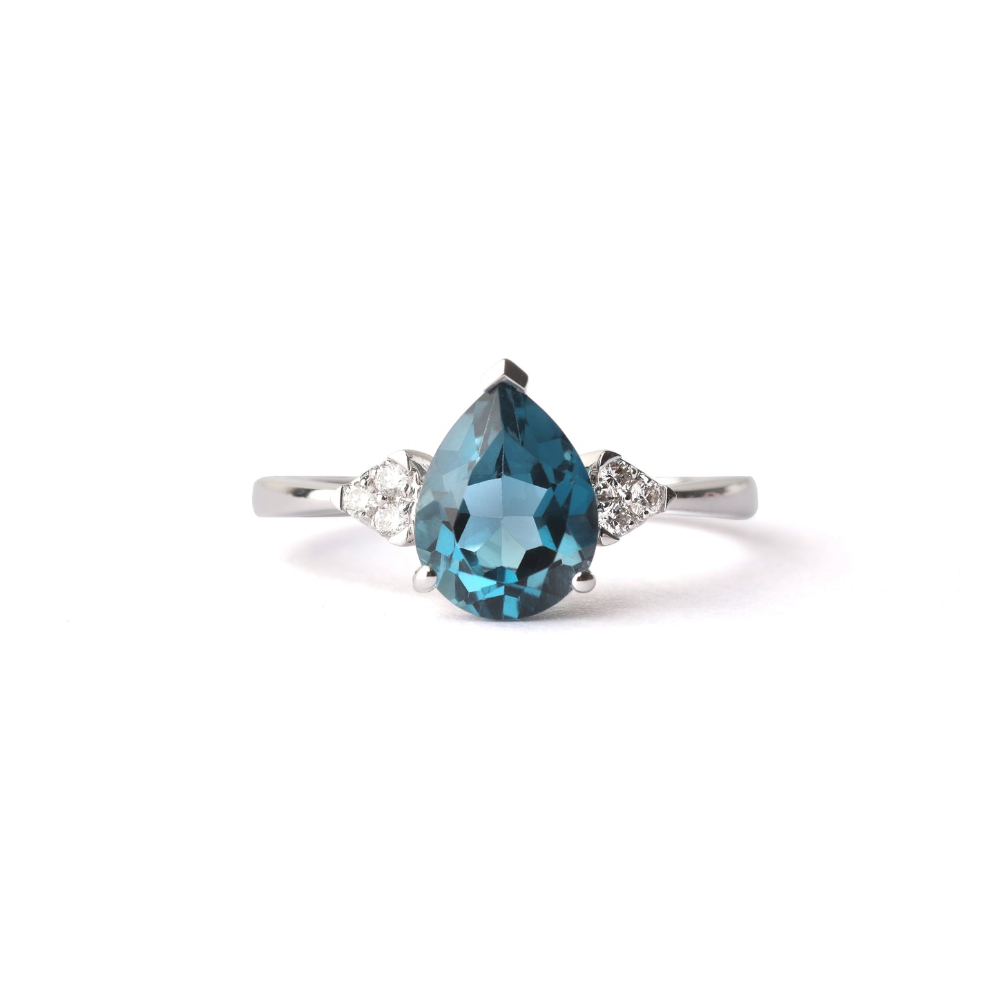 Women's London blue pear shape topaz gemstone claw set on a white gold ring on a white background, with three small diamonds each side of the pear topaz.