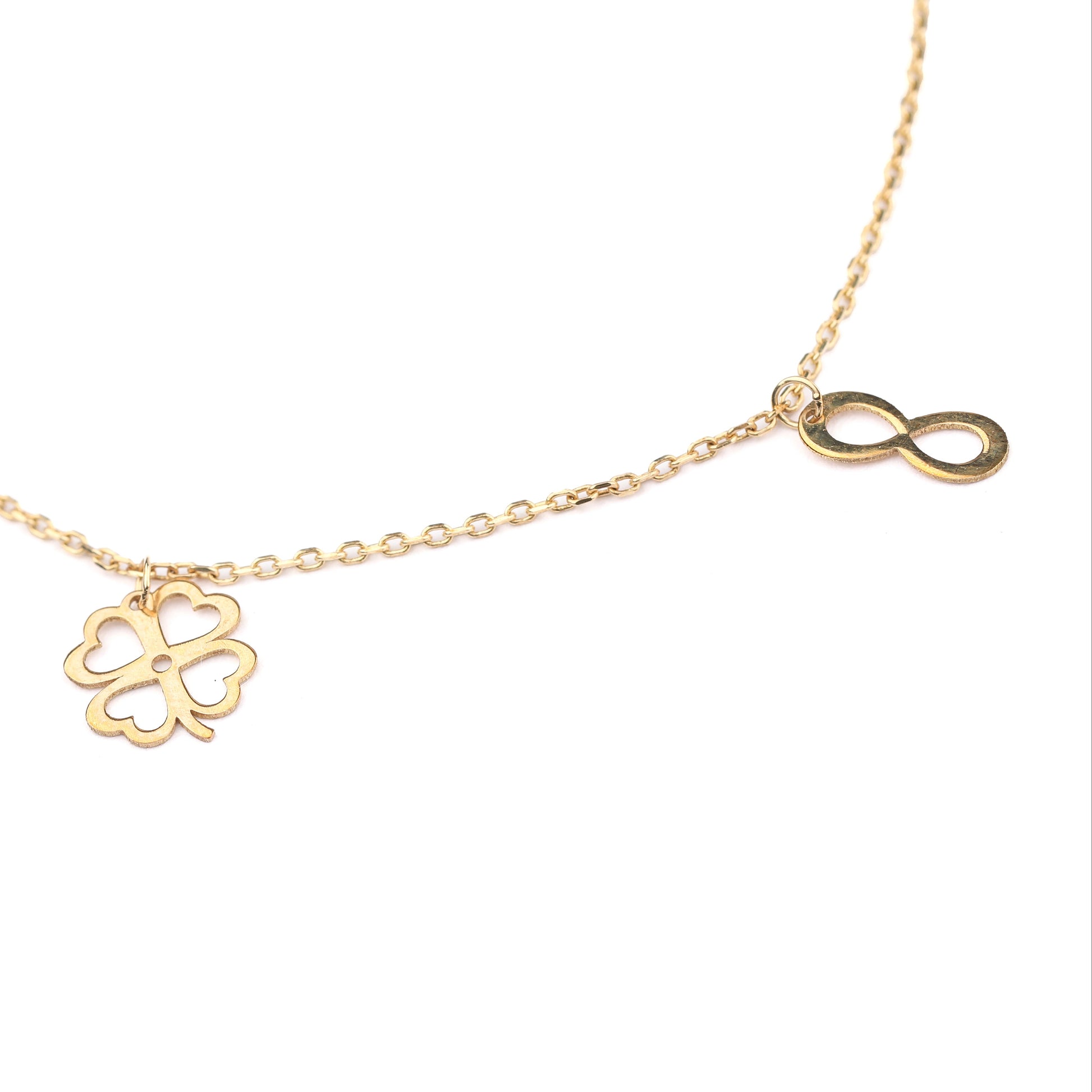 Women's solid gold lucky charm bracelet with clover and infinity symbol charms on a white background