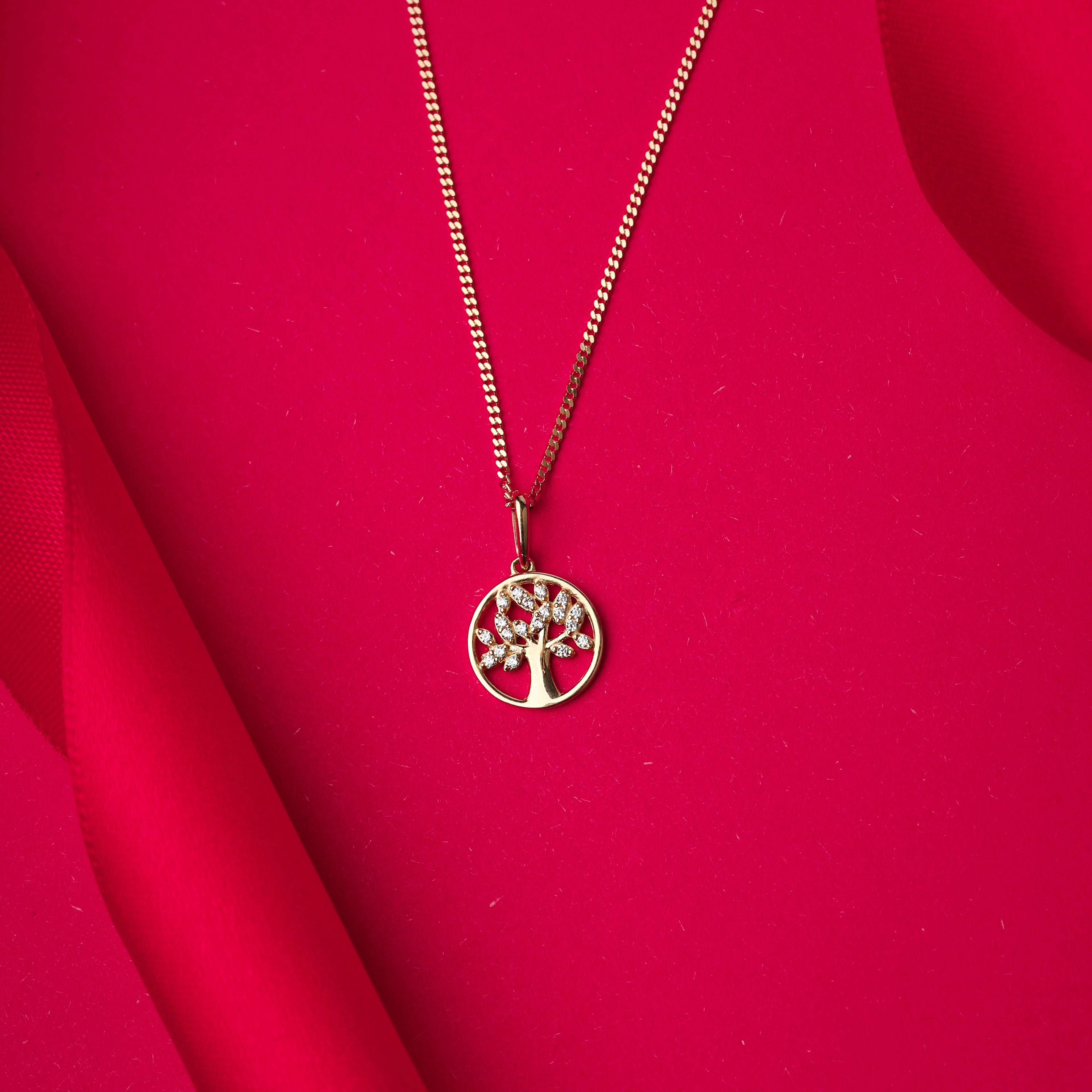 Gold necklace with a tree pendant on a red fabric background
