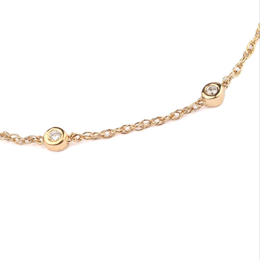Gold necklace with small round diamonds on a white background