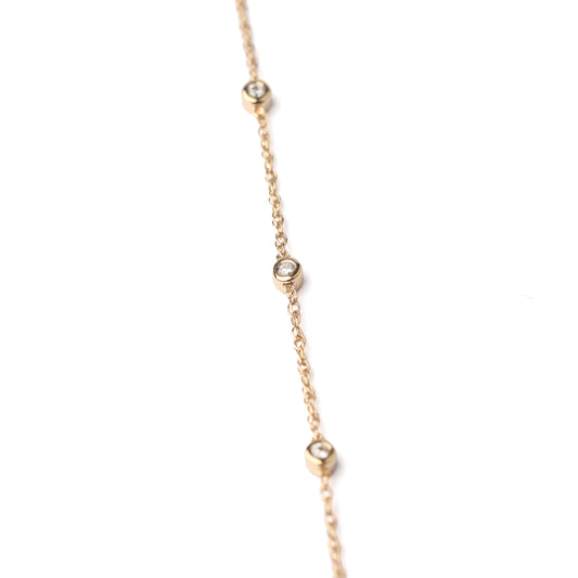 Delicate gold necklace with small diamonds on a white background