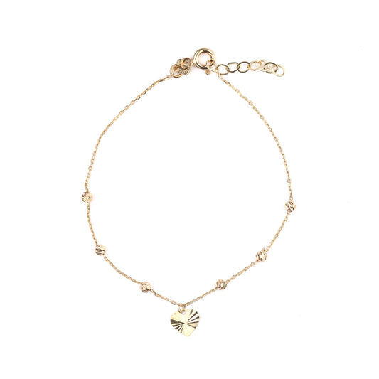 Gold bracelet with a small heart charm on a white background