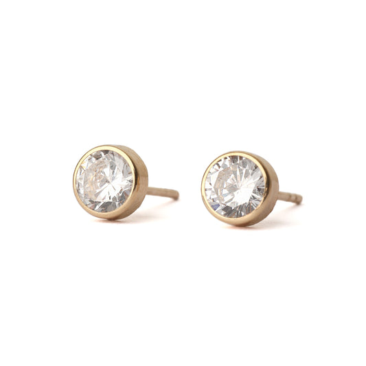 Women's pair of solid yellow gold stud earrings, each with a cubic zirconia gemstones in a bezel setting.  The earrings are displayed facing forward on a white background