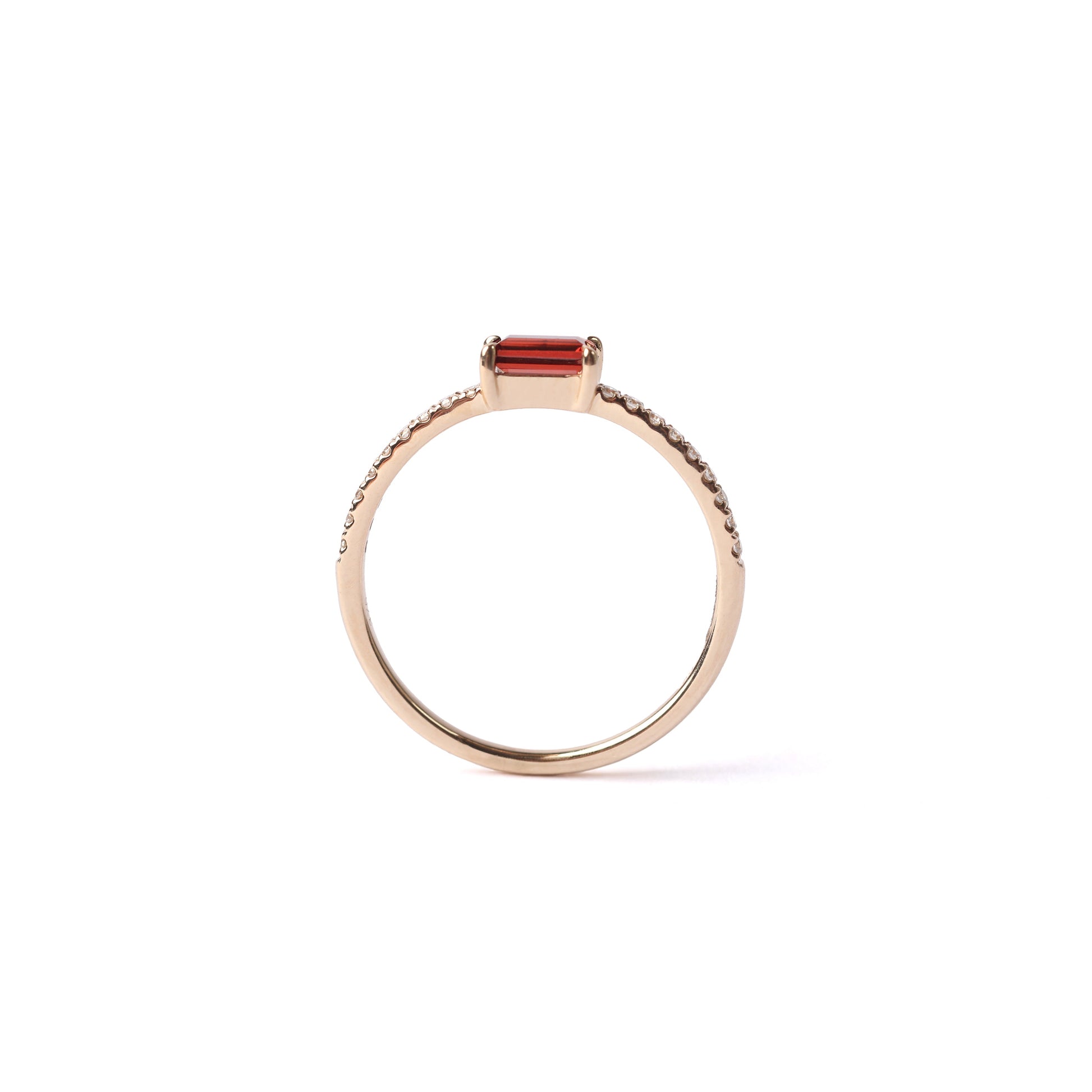 Women's solid yellow gold ring with a rectangular red garnet set as the centre stone, with small round diamonds set into the shoulders of the ring, displayed sideways on a white background.