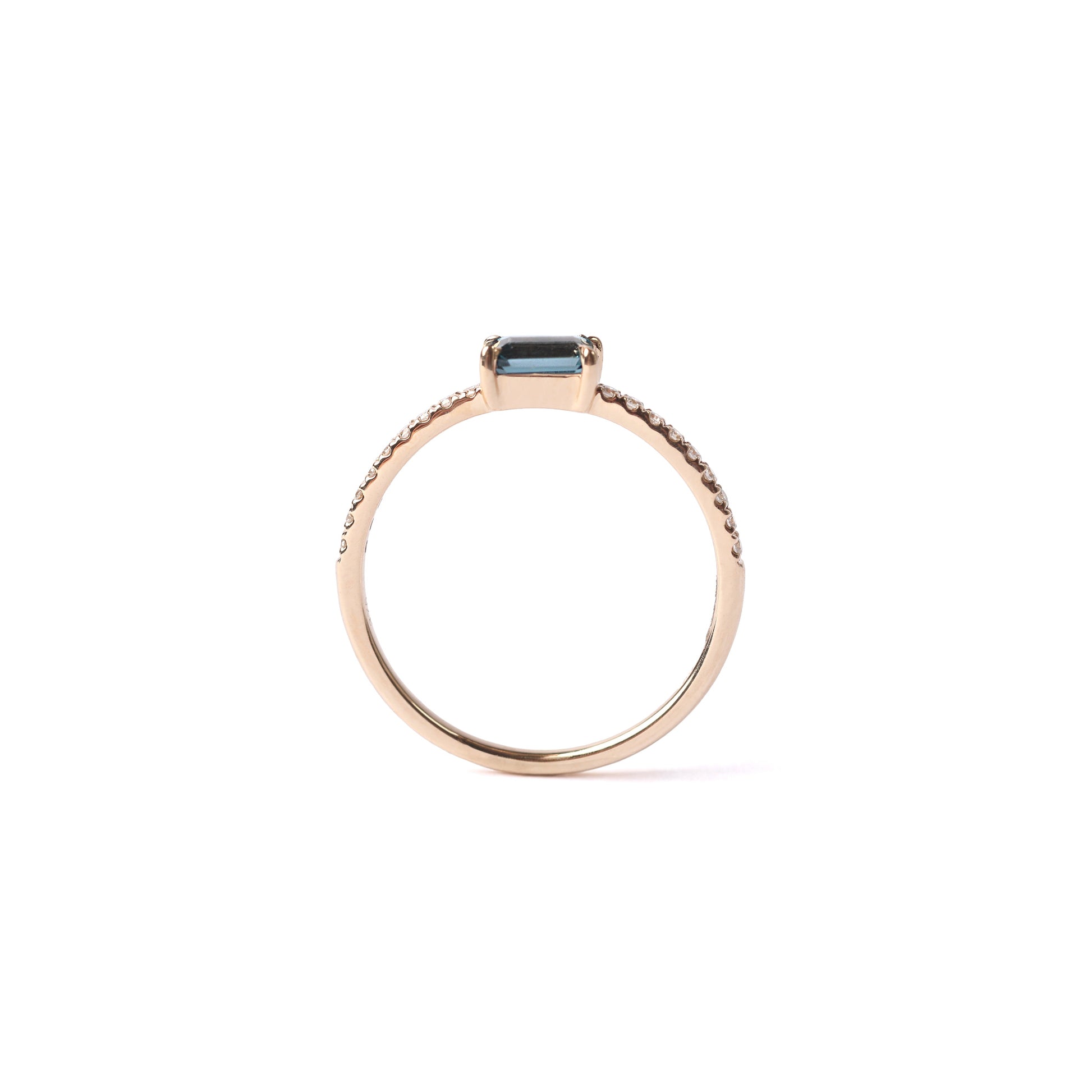 Women's solid yellow gold ring set with a central London blue topaz gemstone and small round diamonds on the shoulders each side of the topaz, displayed on a white background sideways and upright.