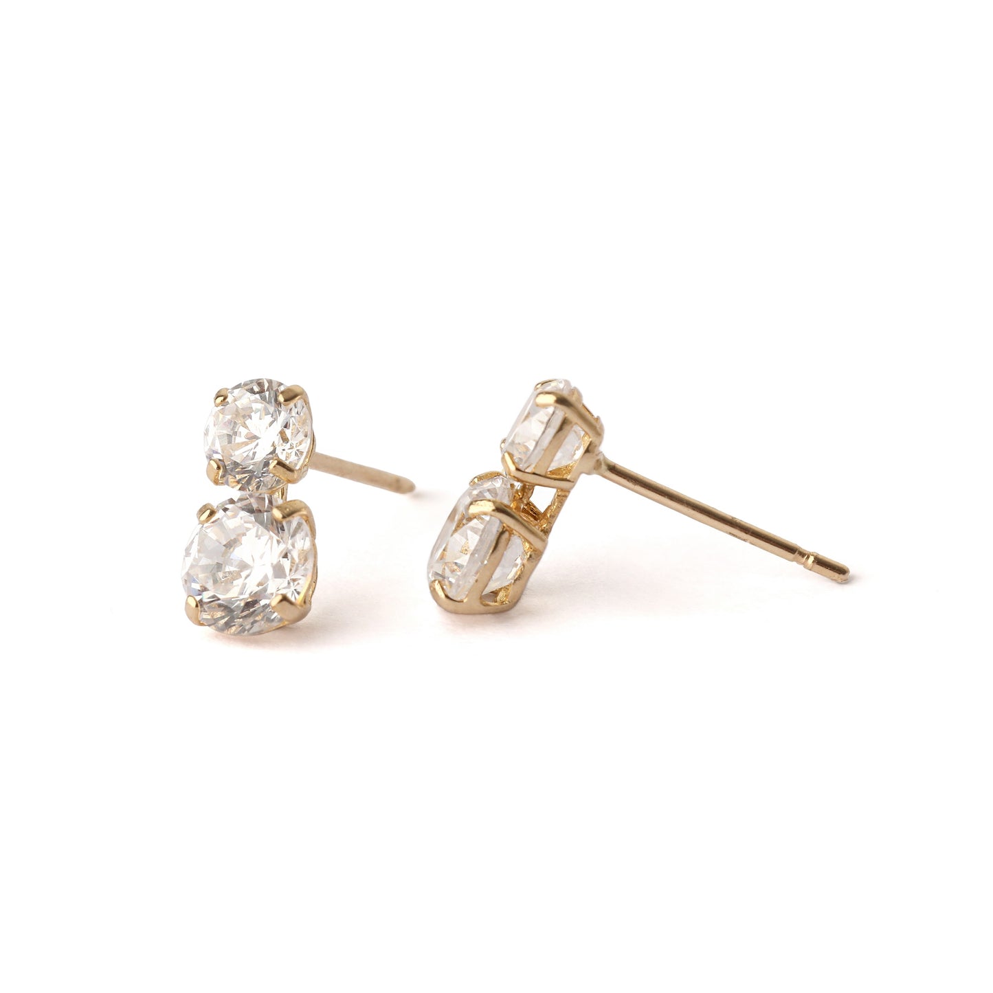 A pair of women's solid yellow gold stud earrings, each with two cubic zirconia gemstones. The top gemstone is slightly smaller the the one below. One earring is face on and the other is displayed with a side profile, and both are on a white background.