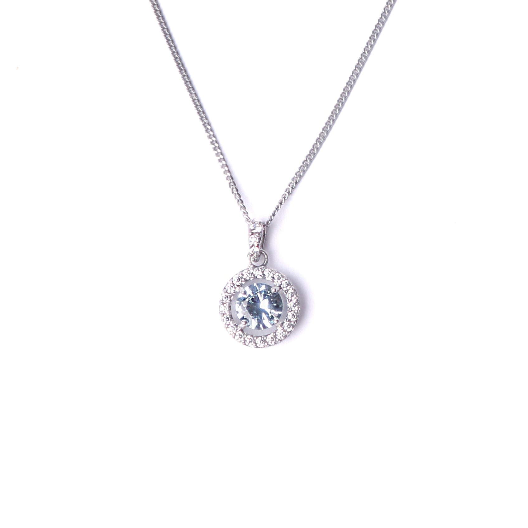 Women's sterling silver and cubic zirconia gemstone pendant, set with a large clue gemstone surrounded by smaller clear cubic zirconia gemstones hanging on a silver chain all set on a white background.